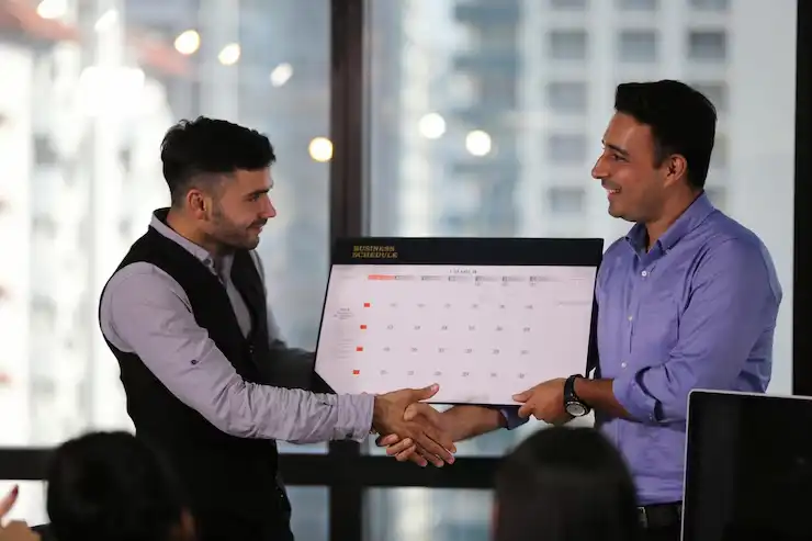 businessmen-shaking-hands-while-holding-calendar-office_1048944-2291534